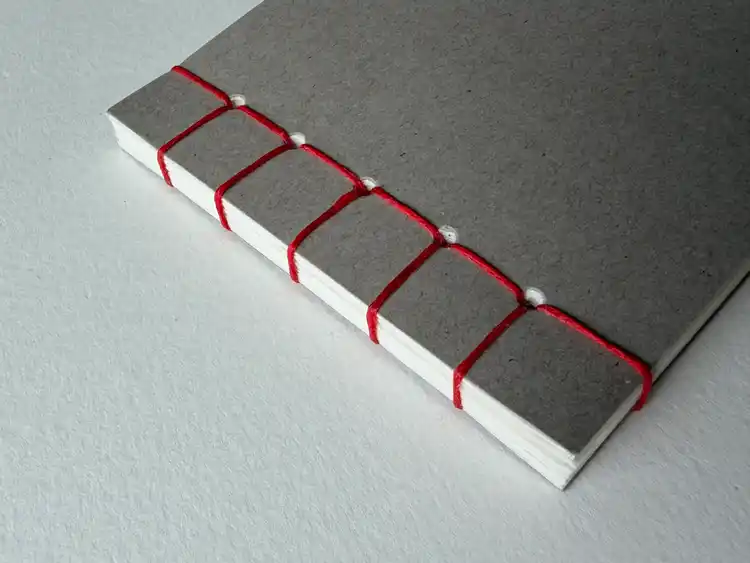 grey notebook bound with red thread